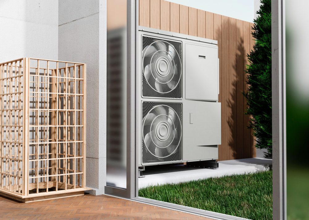 Empresas especializadas acercan soluciones de climatización para proyectos cada vez más eficientes - Outdoor HVAC condenser unit with two large fans mounted inside a glass enclosure beside a wooden privacy screen, with grass nearby.