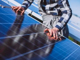 Person in a plaid shirt inspects and touches solar panels in a sunny outdoor installation