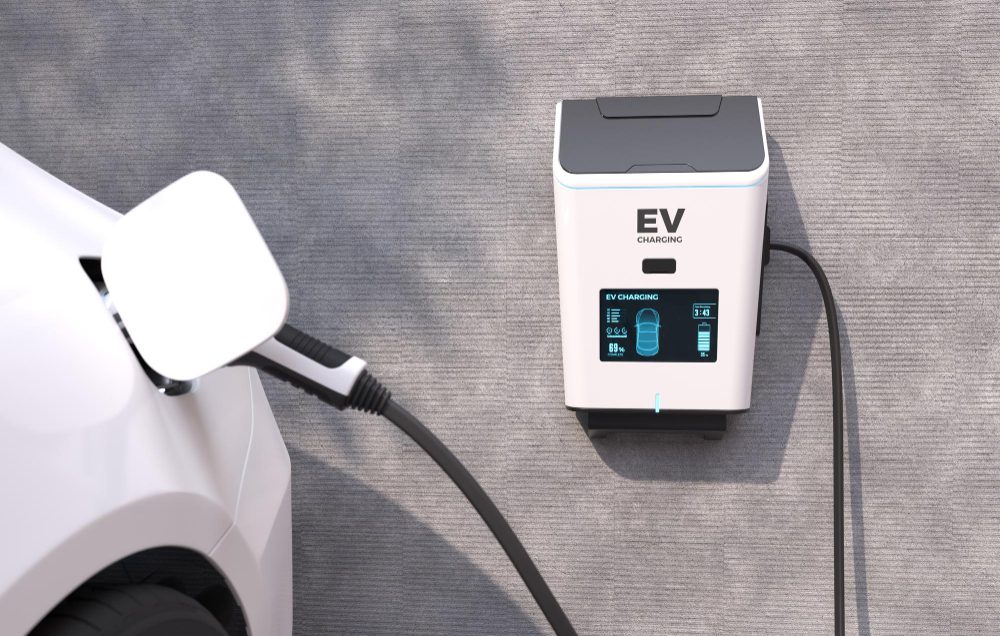 White EV charging unit mounted on the wall with a car's charging cable plugged in.