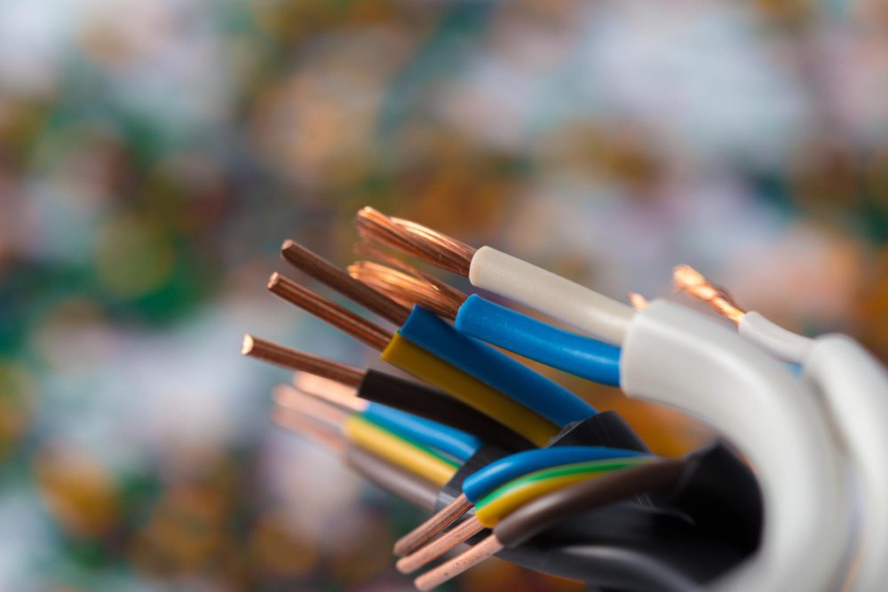 Las instalaciones eléctricas profesionales ganan importancia en nuevos proyectos Close-up of exposed copper wires with colored insulation from multi-conductor cables, held together against a blurred background